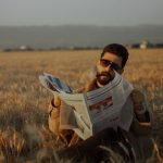 Middle-aged man sitting in a serene wheat field, reading a newspaper during the day. — Beef Casino: Wie steht es um die Spiel