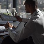 Businessman in office reading sports section, enjoying coffee with city view. — Bet On Red: Gioco Rapido e Vincite Lampo