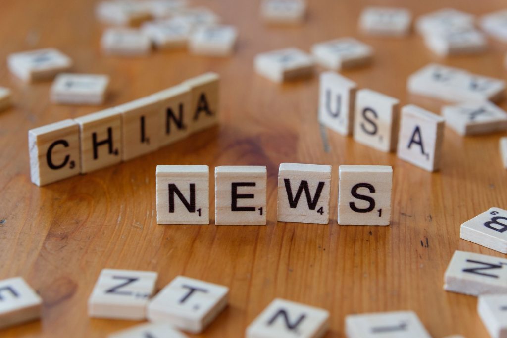 Wooden Scrabble tiles spelling 'NEWS' with 'CHINA' and 'USA' on a wooden surface. — Peut-on vraiment faire confiance aux lice