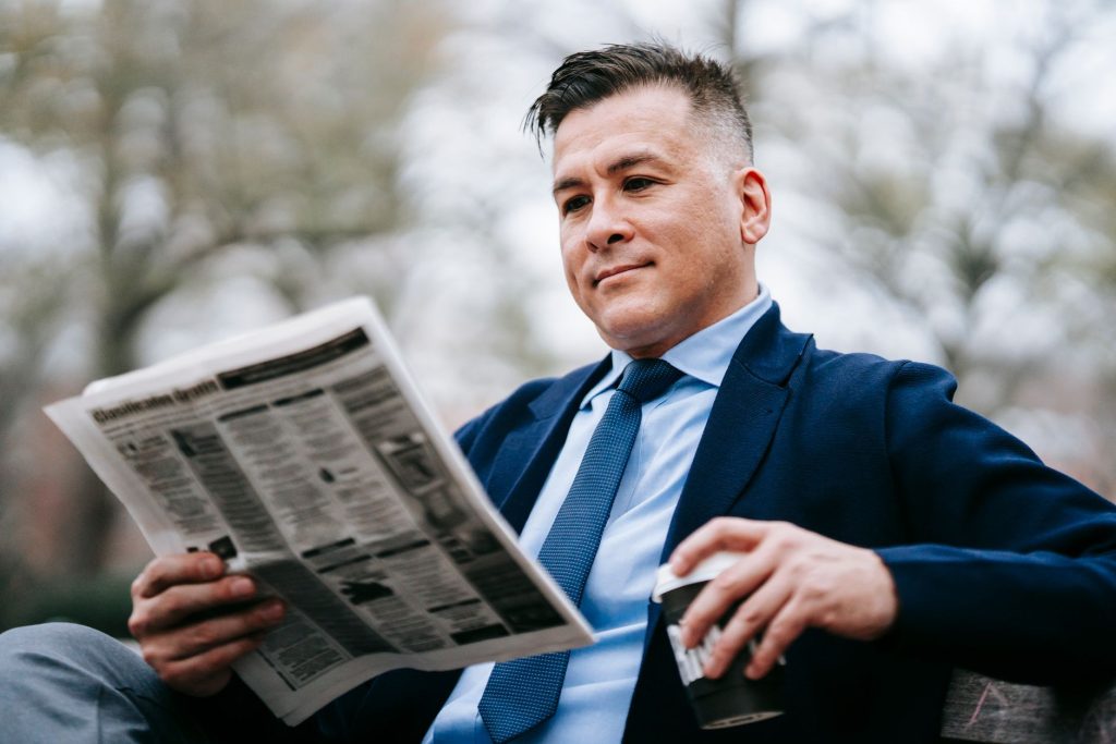 Stylish man in formal wear enjoys a drink while reading a newspaper outside. — Winmate88: Quick Wins and Rapid Play for the M